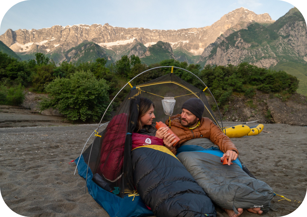 Para w namiocie w górach pije zimną wodę z pomarańczowej butelki filtrującej LifeStraw Go 2.0 Steel
